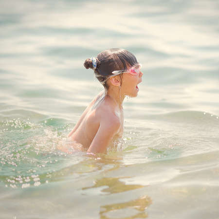 little girl swims and dives to the seaの写真素材