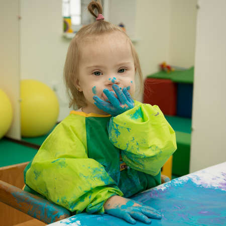Girl with Down syndrome is busy paintingの写真素材