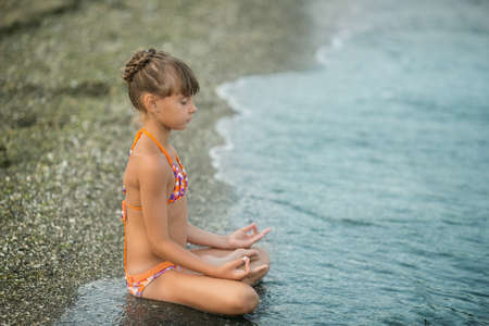 little girl meditating on the beachの写真素材