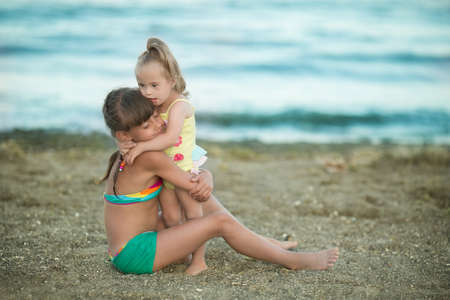 beautiful girl playing with her younger sister with Down syndrome on the beachの写真素材