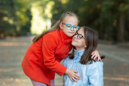 A beautiful girl with Down syndrome lovingly hugs her older sisterの写真素材