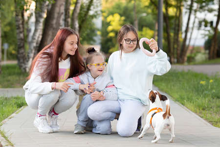 A girl with Down syndrome plays with her sisters while walking the dog Jack Russell