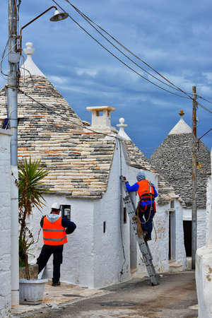 ALBEROBELLO, ITALY - FEBRUARY 11, 2019. Men working in white town of Alberobello, Puglia region, Italyのeditorial素材
