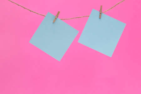 Two bright yellow stickers are hung on a rope with clothespins.