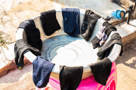 LAMPANG, THAILAND - On January 11, 2019: Laundry socks outdoor in the villagers' old stainless steel tanks, placed on pink plastic chairsのeditorial素材