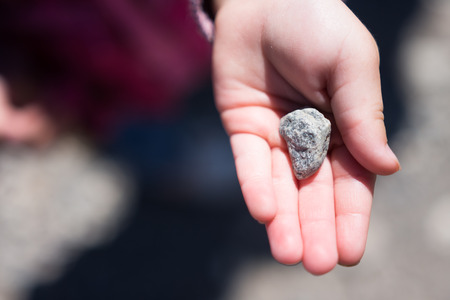 Small child showing off discovered rock in palm of handの写真素材