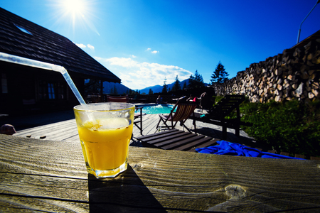 Glass of orange juice on the pool and mountain landscape backgroundの写真素材