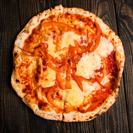 Hot pizza slice with melting cheese on a rustic wooden table.の写真素材