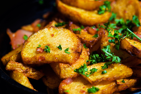 baked fried potatoes with garlic on wooden table backgroundの写真素材