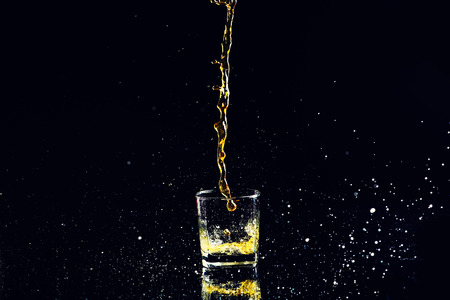Isolated shot of whiskey with splash on black background, brandy in a glassの写真素材