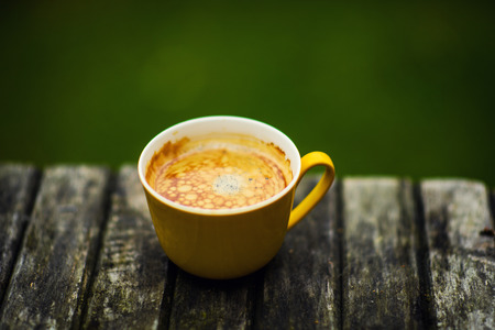 A yellow cup of tasty coffee, on rustic wooden table backgroundの写真素材