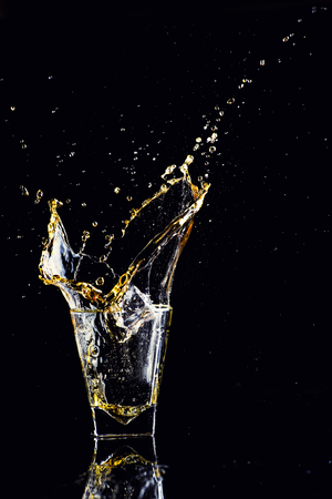 Isolated shot of whiskey with splash on black background, brandy in a glassの写真素材