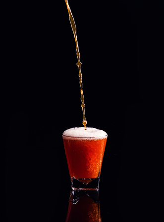 Isolated shot of whiskey with splash on black background, brandy in a glassの写真素材