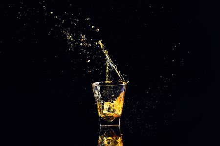 Isolated shot of whiskey with splash on black background, brandy in a glassの写真素材