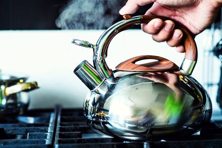Tea kettle with boiling water on gas stoveの写真素材