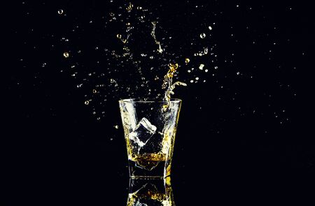 Isolated shot of whiskey with splash on black background, brandy in a glassの写真素材
