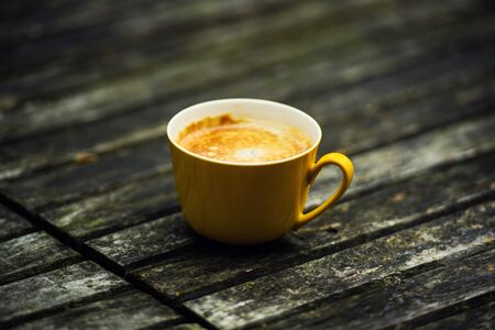 A yellow cup of tasty coffee, on rustic wooden table backgroundの写真素材