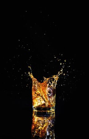 Isolated shot of whiskey with splash on black background, brandy in a glassの写真素材