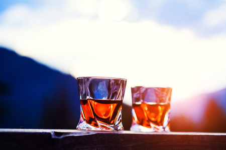shot of whiskey at sunset dramatic sky on mountain landscape backgroundの写真素材