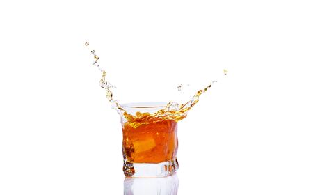 Whiskey with splash on white background, brandy in a glassの写真素材