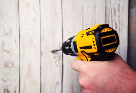 cordless drill and a drill on a wooden backgroundの写真素材