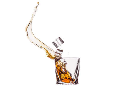 A glass of whiskey with splashes from the ice cube isolated on white. alcohol splashes. whiskey or cognac or another type of alcohol.の写真素材