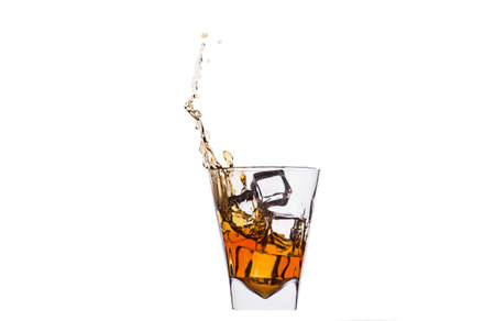 A glass of whiskey with splashes from the ice cube isolated on white. alcohol splashes. whiskey or cognac or another type of alcohol.の写真素材