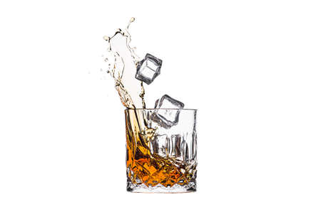 A glass of whiskey with splashes from the ice cube isolated on white. alcohol splashes. whiskey or cognac or another type of alcohol.の写真素材