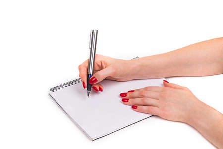 Nails Design. Hands With Bright Red Christmas Manicure On White Background. Close Up Of Female Hands. Art Nail. woman writes with a pen in a notebookの写真素材