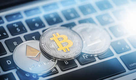 Bitcoin and other cryptocurrencies are placed on a laptop keyboardの写真素材