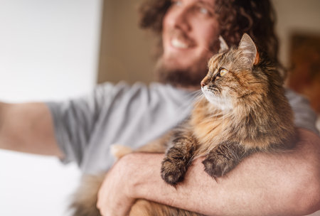 A happy man is looking out the window together with a catの写真素材