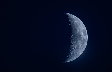 Half-moon glowing in the deep blue sky, creating a serene and celestial atmosphere.の写真素材