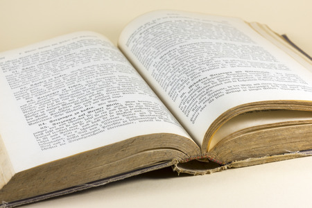 Old book open to printed pages lying on an off white background viewed low angle in a conceptual imageの写真素材