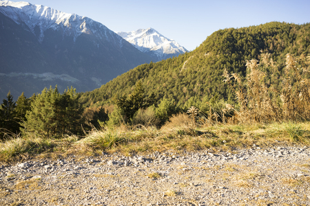 Scenic mountain landscape background with snowy peaks and forested slopes in autumn or early winterの写真素材
