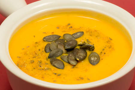 Delicious bowl of homemade autumn pumpkin soup garnished with spices and dried pumpkin seedsの写真素材