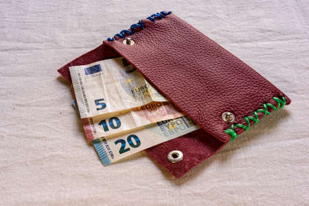 Euro banknotes in different denominations, protruding from an open purse on a table,の写真素材