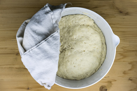 Top down view of bread batter rising in bowl. Cloth rag on top to cover it for enhancing the speed of yeast activationの写真素材