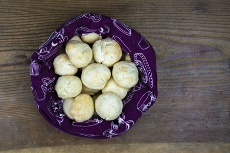 Overhead view of freshly baked bread buns in a bag on wood table with copy space