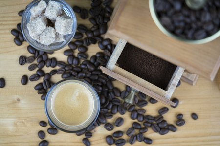 Coffee grinder with espresso and sugar cubes served in small glasses viewed from above with focus to the open drawer with ground beansの写真素材