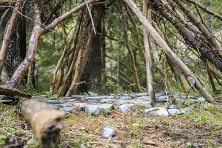 Stones arranged below a tent of branches arranged in a wigwam shape viewed low angle outdoors in a clearing in a forestの写真素材