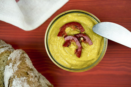 Rustic sliced rye bread and authentic homemade curry hummus garnished with beautiful red capsicum slicesの写真素材