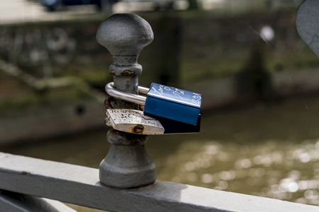 Two padlocks fixed at bridge railing as symbol of loveの写真素材