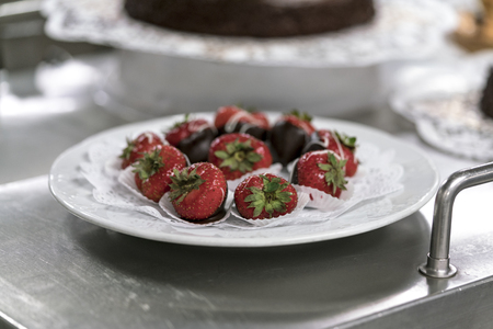 Fresh strawberries served on white napkin on the plate over metal stand in restaurant. Viewed in closeup from the sideの写真素材