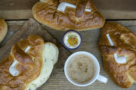 Home baked St. Martin's day Weckmann sweet breads with coffee and warm beverages on a rustic timber table.の写真素材