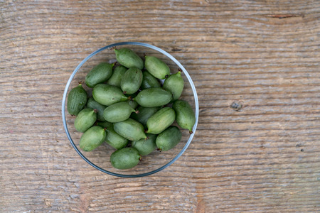 A high angel close up of fresh green kiwis in a bowl on a rustic timber table.の写真素材