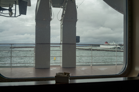 A window view over the deck and harbour from a large, commercial ship.の写真素材