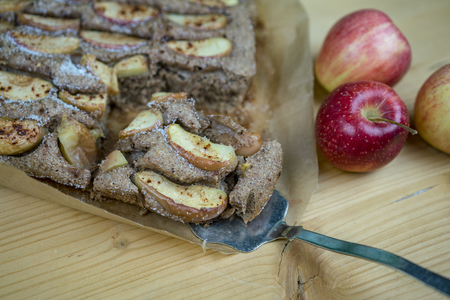 Taking the piece of apple pie with metal cake spatula. Fresh whole red apples also on the wooden table. Viewed in closeup from high angleの写真素材