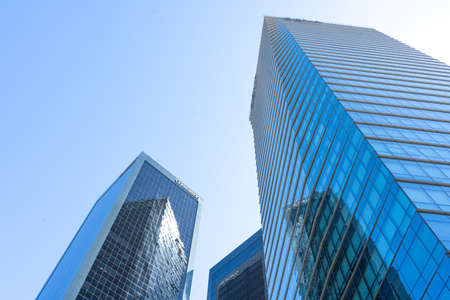 Skyscraper glass facades on a bright sunny day with sun beams in the blue sky. Modern buildings of...