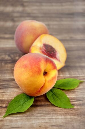 ripe peach with leaf isolated on wood  backgroundの写真素材