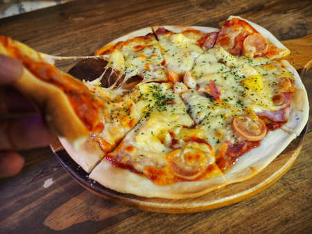 Homemade Slice Pizza with hand pull piece of melt Cheeseの写真素材